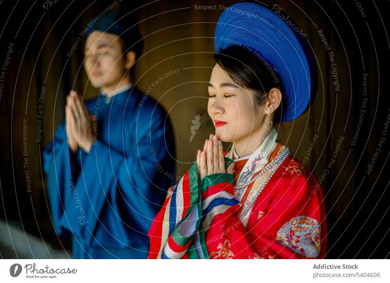 Stylish Asian couple in traditional clothes praying hat worship outfit portrait hands clasped positive veranda asian couple together devotion soulmate partner