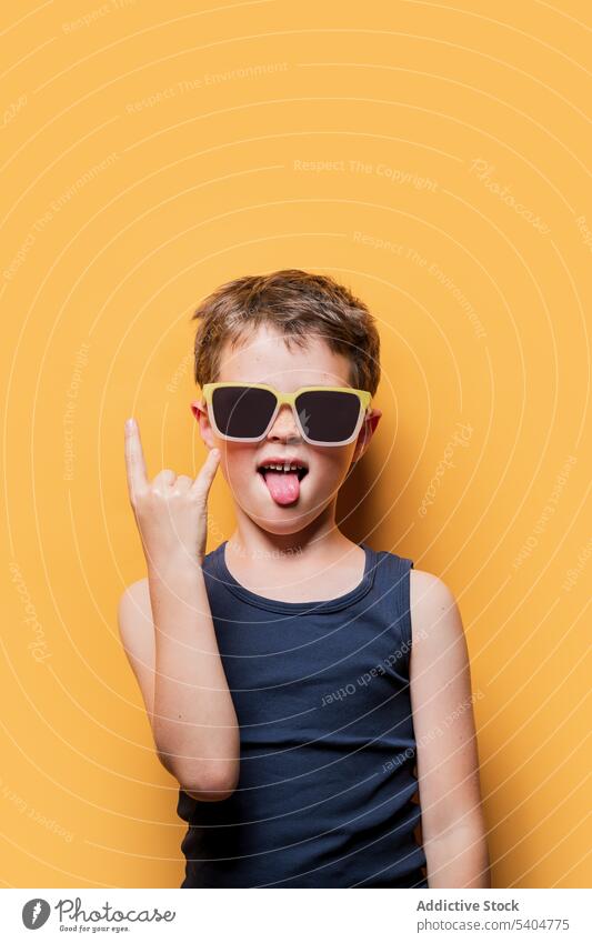 Cool boy in sunglasses showing rock and roll sign cool rebel horn rocker style child preteen gesture kid symbol accessory tank top personality generation