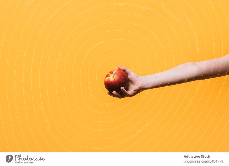 Crop kid with apple over yellow background fruit fresh hand child show healthy yummy food vitamin ripe delicious organic natural sweet nutrition edible vivid