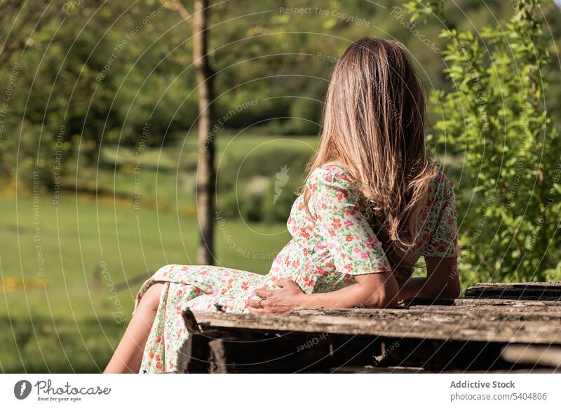 Anonymous female on bench in countryside woman leisure summer table rest tranquil harmony rural dress relax calm style carefree serene natural idyllic alone