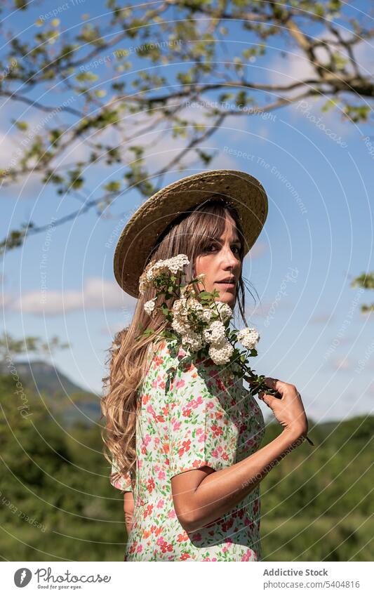 Calm woman with flowers in summer countryside dream nature field blossom bouquet romantic dress garden rural straw hat meadow idyllic peaceful harmony serene