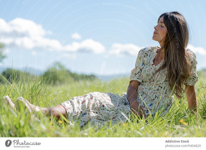 Dreamy woman resting on grass in valley enjoy summer countryside lawn nature harmony relax green serene freedom meadow dress calm female sit gentle field chill