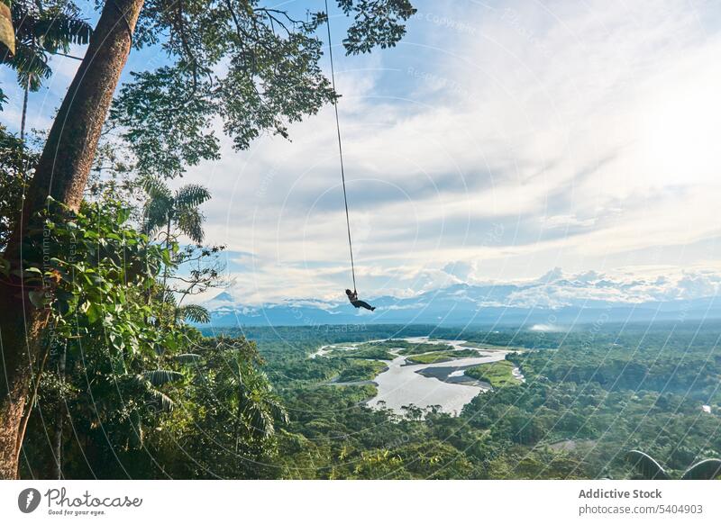 Man swinging in tropical valley with green trees man rope landscape mountainous nature environment jungle foliage greenery picturesque countryside woods forest