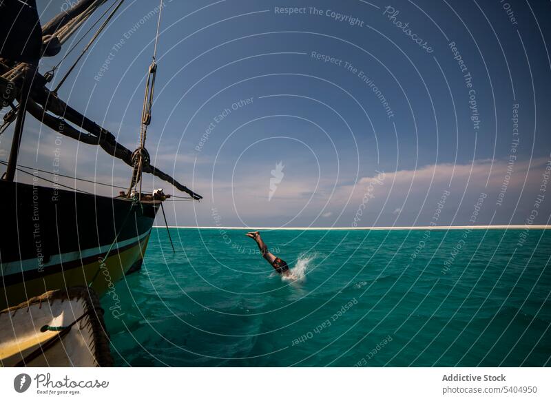 Man diving into sea from yacht man dive sailboat activity swim ocean cloudy water marine wetsuit aqua scenic swimsuit sky nature faceless swimmer seascape hobby