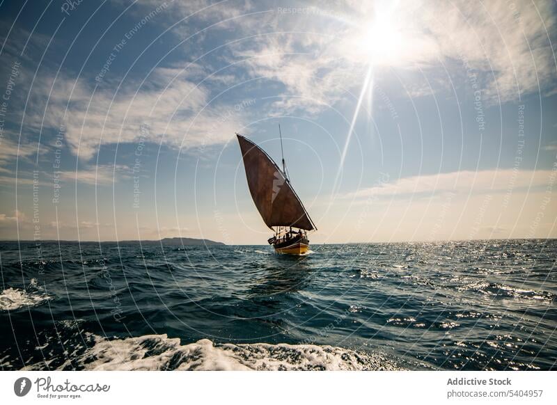 Sailboat floating in sea against blue cloudy sky sail rope tied moor deck transport daytime sailboat marine voyage bright calm ripple blue sky fishing