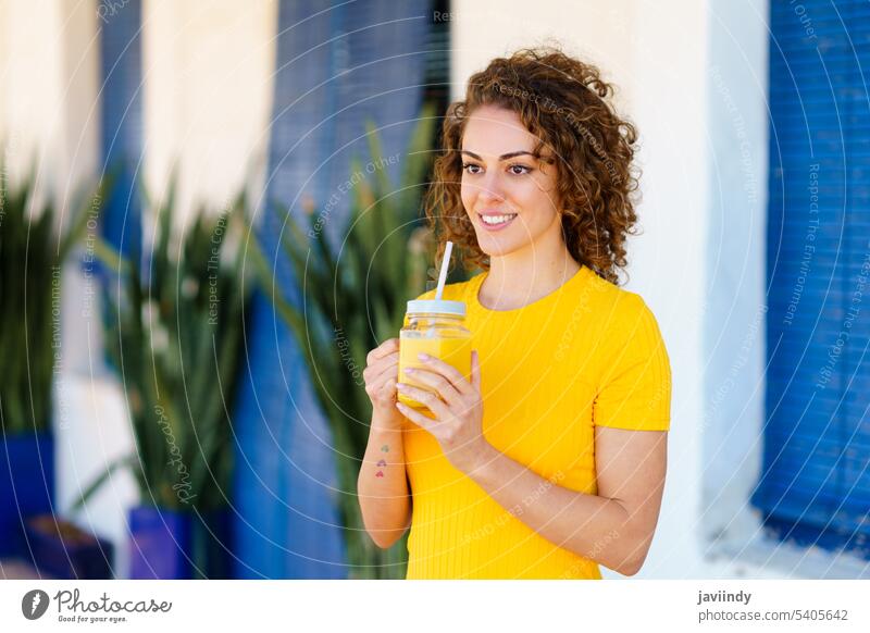 Smiling woman with refreshing drink smiling on the street Woman Juice Drinking Happy Fresh Orange Healthy Summer Café Positive Cheerful youthful Beverage Straw