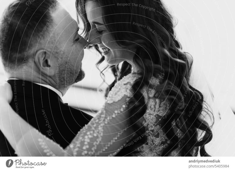Young couple in love bride and groom posing in studio on background decorated with Christmas tree in their wedding day at Christmas. Enjoy a moment of happiness and love. black and white photo