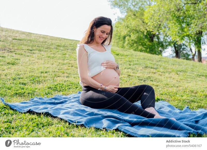 Happy pregnant woman in green park expect belly maternal grass street cheerful rest happy female pregnancy await childbearing prenatal motherhood anticipate