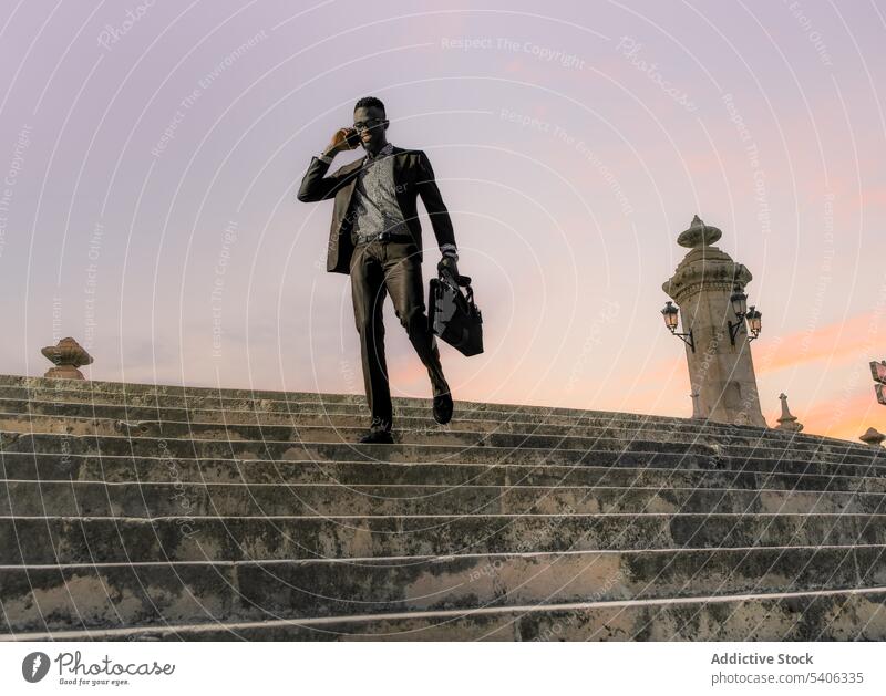 Stylish black businessman speaking on phone walking down stairs phone call confident smartphone trendy style street mobile urban town formal well dressed device