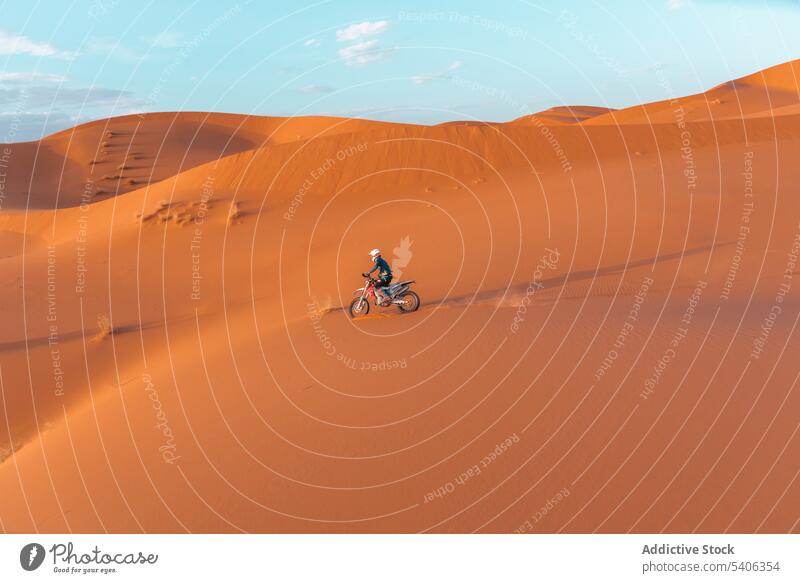 Unrecognizable traveler riding bike in desert person ride motorbike sand dune adventure biker transport extreme morocco sky motorcycle landscape trip arid