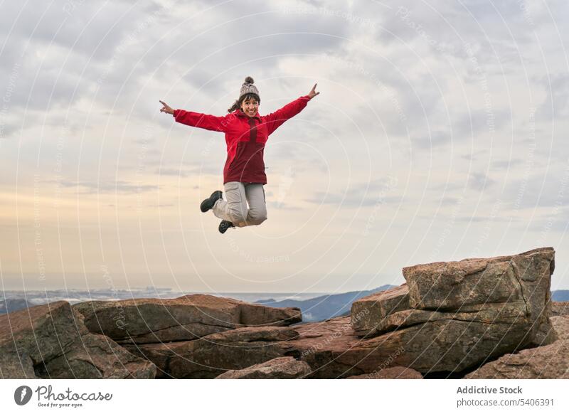 Carefree woman jumping on mountain cliff during sundown excited traveler trekking success rocky el garbi sunset happy nature female sky outwear adventure