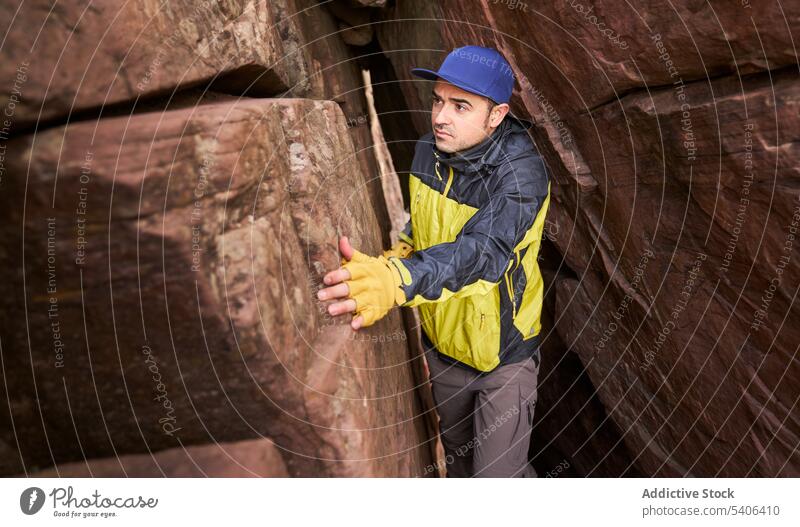 Tourist in narrow gap of cave man tourist trip passage rocky explore formation climb male traveler mountain vacation tourism guy hike expedition activity
