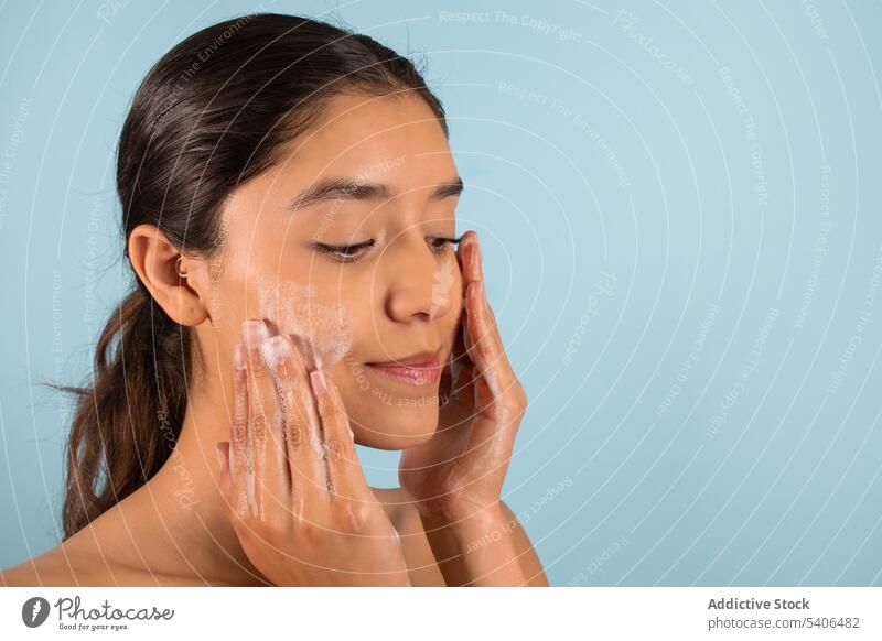 Ethnic woman applying soap on cheeks during beauty procedure foam cosmetic product skin care routine cosmetology smile positive female ethnic facial treat