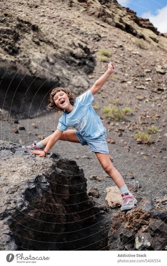 Cheerful kid enjoying freedom in rocky terrain near mountain smile stone happy cheerful positive stretch lean on hand child preteen girl nature childhood