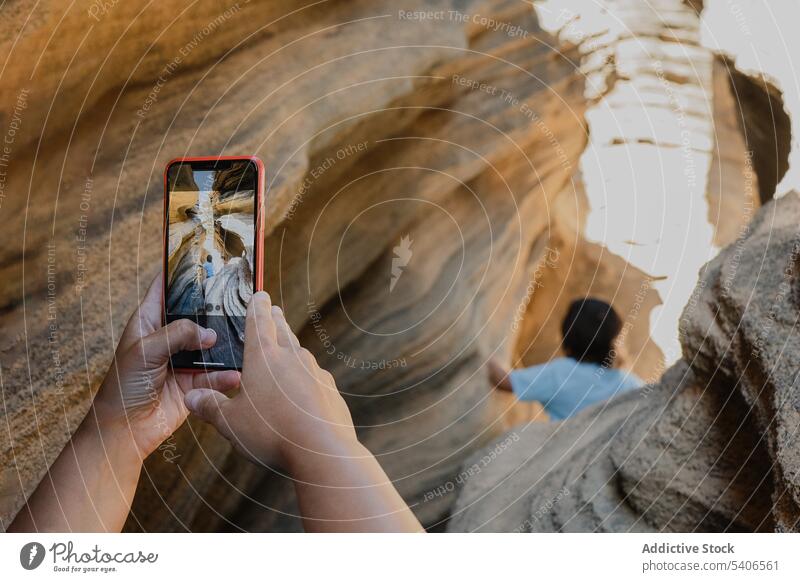 Unrecognizable person taking photo of anonymous kid on smartphone take photo cliff child climb rocky mountain using photography gadget device stone admire