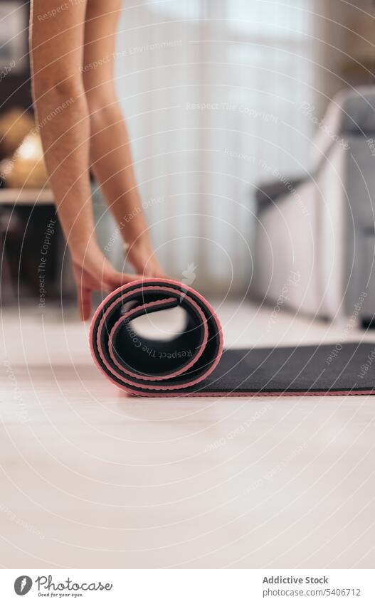Anonymous person rolling up mat at home roll up yoga training healthy lifestyle fitness workout wellbeing equipment exercise wellness physical supply activity