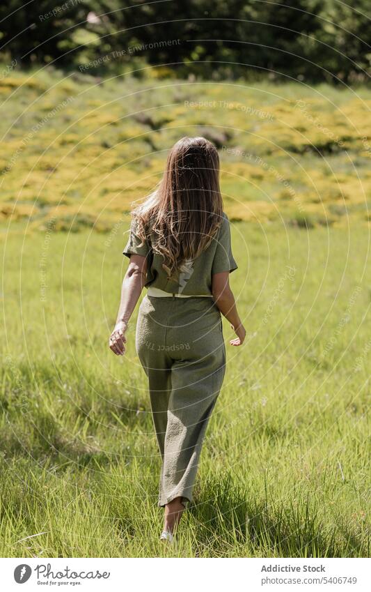 Unrecognizable woman walking in green field forest summer lawn weekend park enjoy nature grass countryside relax casual female plant environment grassy flora