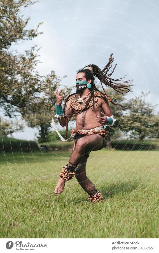 Happy man in traditional costumes and flying hair dancing outdoors dance park mask perform having fun accessory celebrate positive joy cheerful young male