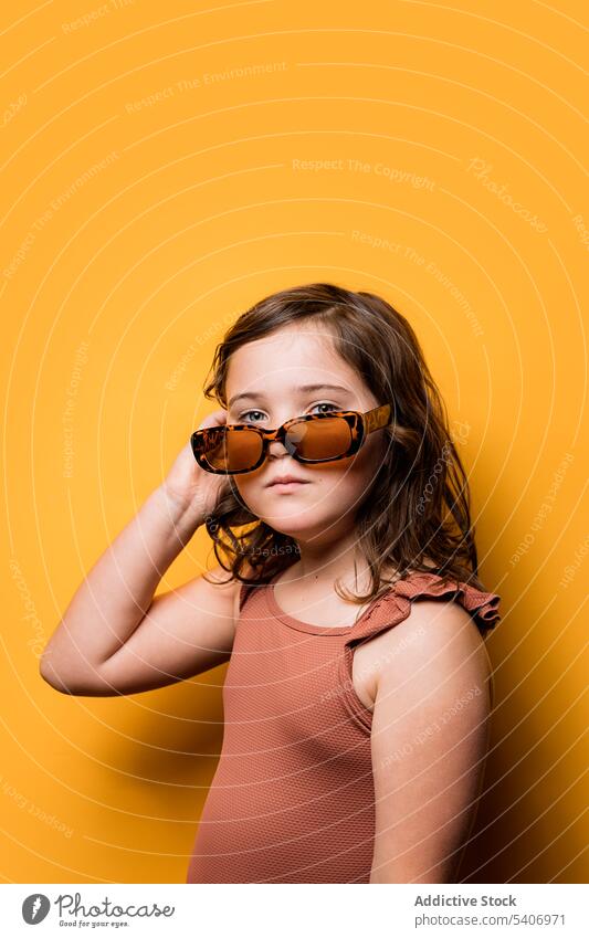 Cute little girl in sunglasses touching hair and looking at camera style touch hair confident child summer holiday cool portrait serious model fashion kid