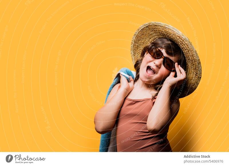 Happy adorable child adjusting sunglasses against yellow background mouth opened cheerful summer excited happy girl portrait vacation positive joy style kid