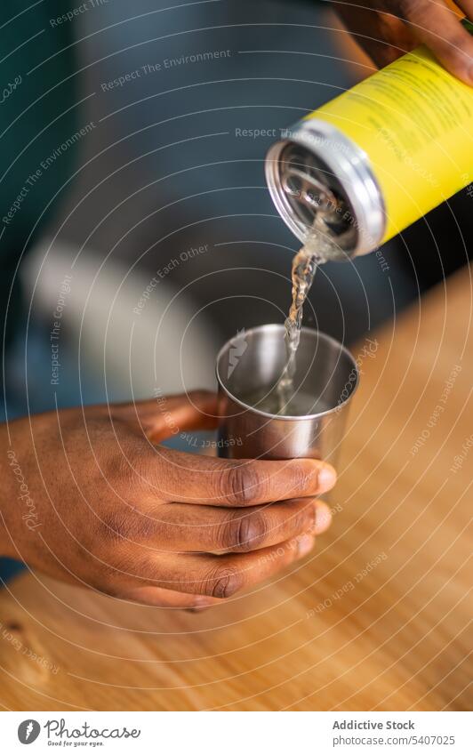 Crop person pouring canned drink into cup hand bottle stainless beverage soda table serve tasty alcohol liquid refreshment portion delicious nutrition yummy