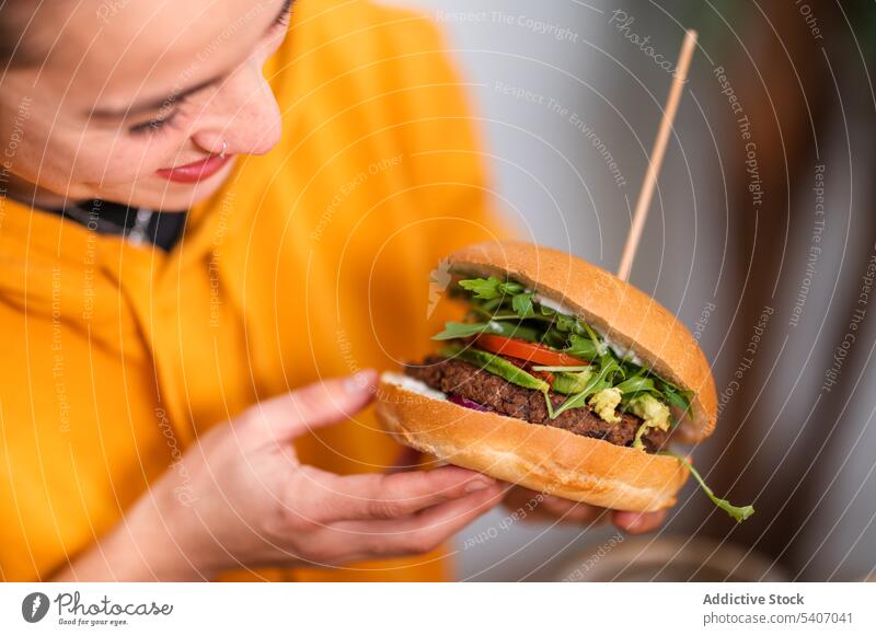 Smiling woman eating burger at restaurant delicious positive food tasty female break cafeteria smile yummy vegetable enjoy lunch casual meal young happy