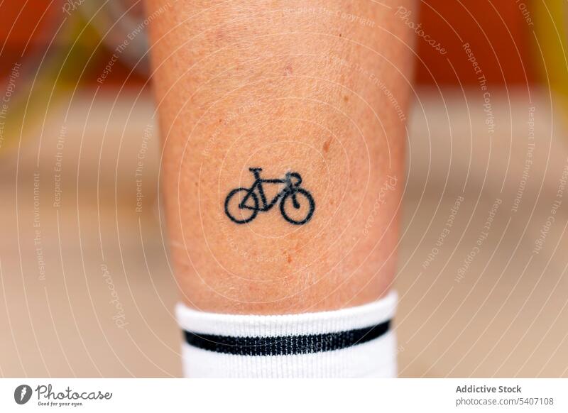 Unrecognizable person with small bicycle tattoo on leg standing in daylight temporary minimal bike street white sock summer alone figure style trendy daytime