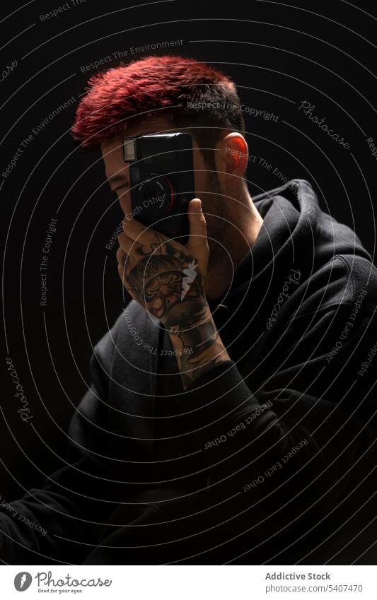 Young anonymous man taking photo on camera photo camera photographer portrait tattoo shoot dyed hair take photo studio lens style film creative retro trendy