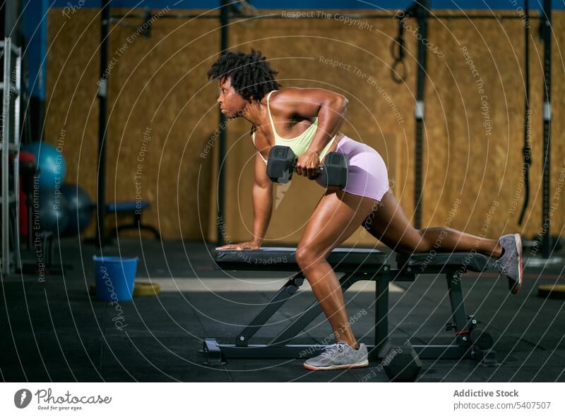 Black athlete exercising on bench with dumbbell sportswoman exercise weightlifting heavy training workout fitness mature afro african american black ethnic