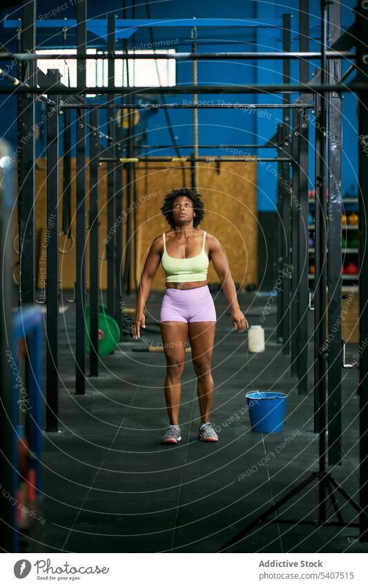 Fit black sportswoman exercising on monkey bars in gym exercise training strong muscular challenge healthy workout fitness jump pull up mature afro