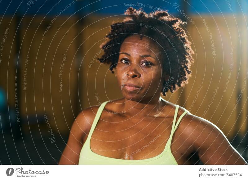 Black mature sportswoman with Afro hairstyle portrait confident training strong muscular fitness gym healthy lifestyle wellness emotionless afro