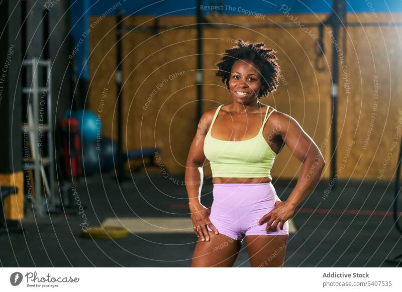 Happy black mature sportswoman with Afro hairstyle confident training strong muscular fitness gym healthy lifestyle wellness emotionless smile content afro