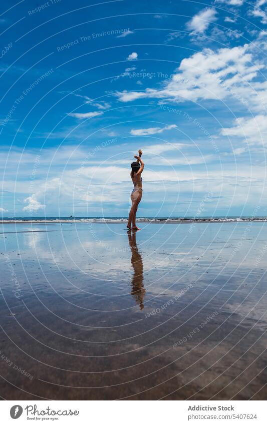 Woman standing on wet beach against blue sky with clouds woman wave sea ocean resort reflect arms raised sand shore carefree female young uvita puntarenas