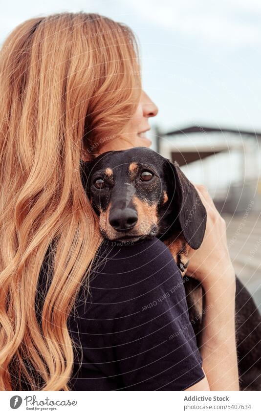 Smiling young woman hugging dog during walk owner stroll spend time dachshund cuddle embrace pet street companion purebred breed adorable friend daytime