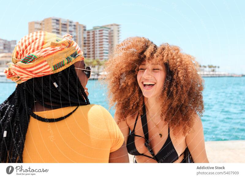 Group of cheerful multiethnic women in city friend stroll laugh together waterfront having fun summer group multiracial diverse black african american seafront