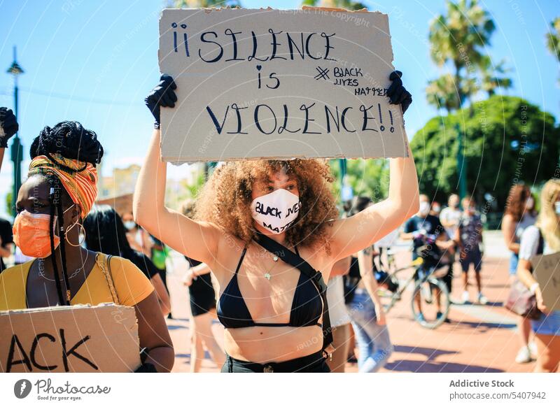 Woman with poster silence is violence in city black lives matter crowd street protest woman demonstrate racism activist female ethnic multiracial diverse people