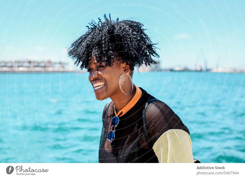 Charming black woman on embankment in city seafront waterfront enjoy relax sunny hairstyle charming smile female ethnic african american cheerful happy summer