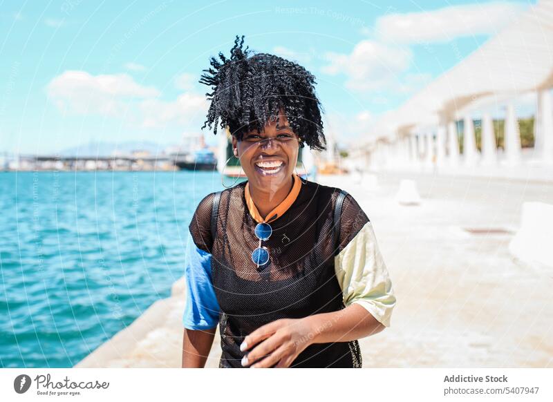 Charming black woman on embankment in city seafront waterfront enjoy relax sunny hairstyle charming smile female ethnic african american cheerful happy summer