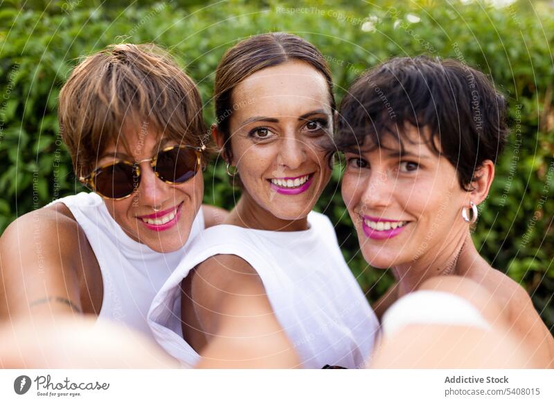 Lovely friendly women taking selfie in city park self portrait friendship adult cheerful summer company together happy female smile enjoy hug delight group