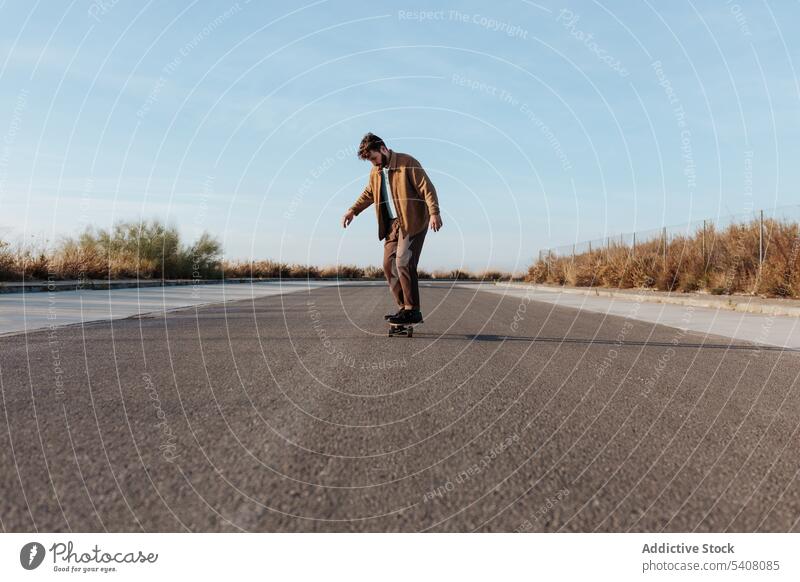 Young bearded skater on asphalt road man ride skateboard countryside rural nature hobby subculture practice skill male energy cool motion sport balance move