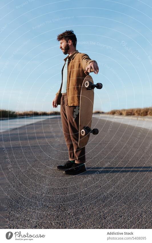 Bearded skater throwing skateboard on road man countryside longboard serious hobby fall cool trick skill male activity rural asphalt subculture energy levitate