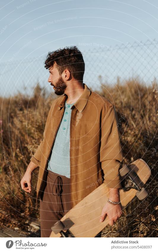 Young skater looking away man cheerful freedom countryside nature skateboard laugh hobby subculture male joy positive cool young beard casual optimist content
