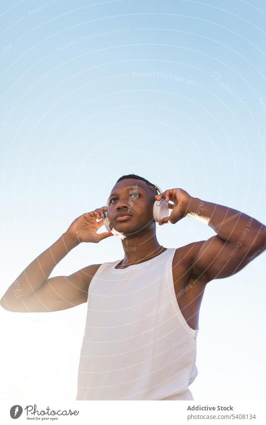 Black sportive man listening to music runner anonymous using headphones training athlete workout break sportsman gadget sportswear wireless lifestyle modern