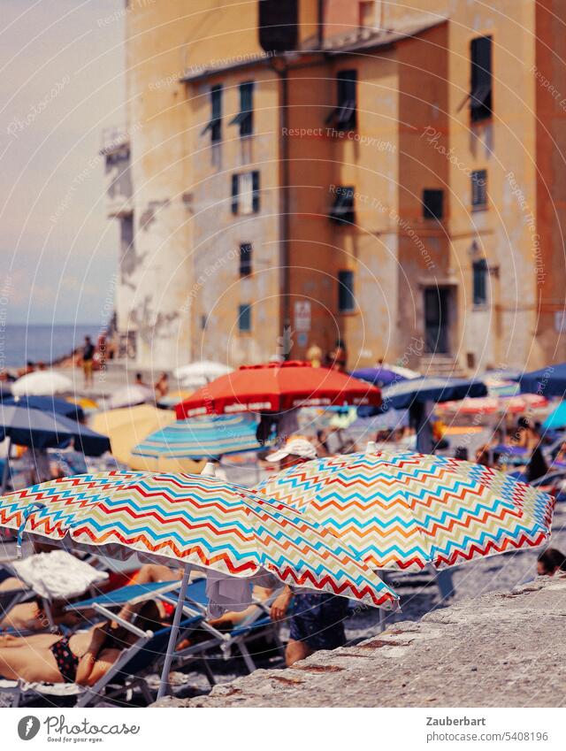 Colorful parasols in front of ocher houses on the beach of the Italian Riviera Sunshade variegated Ochre Beach bathe vacation Relaxation Italy Vacation & Travel