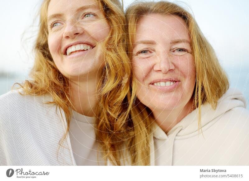 Redhead senior mother and her beautiful adult daughter are walking together and laughing family redhead grown up child look alike people portrait mom generation
