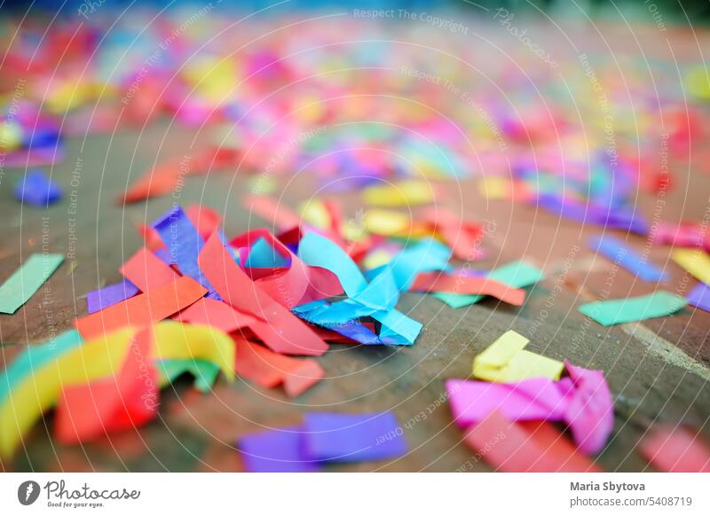 Multicolour paper ticker-tape lies on the ground after celebration of wedding, birthday, carnival, lgbt pride parade or outdoors festival. After party.