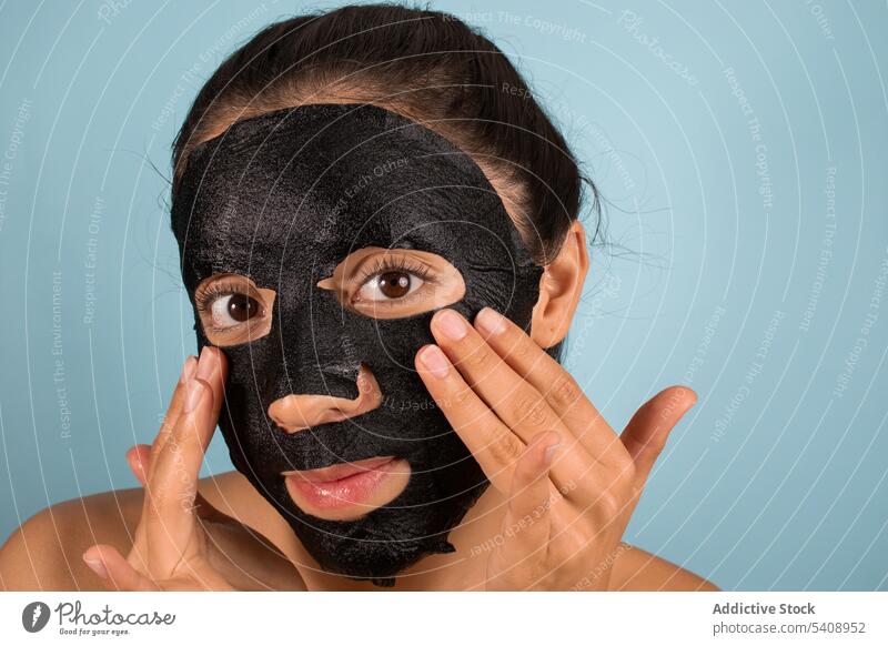 Woman with mask on face in studio woman skin care bamboo charcoal mask cosmetic beauty routine apply facial portrait female cosmetology procedure appearance