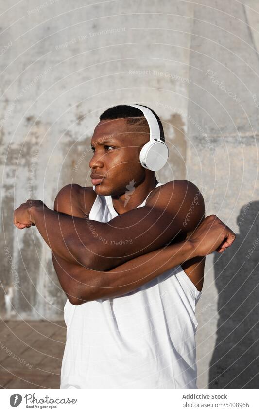 Black runner stretching neck before training on street man warm up concentrate exercise fitness athlete headphones energy male active cardio confident sporty