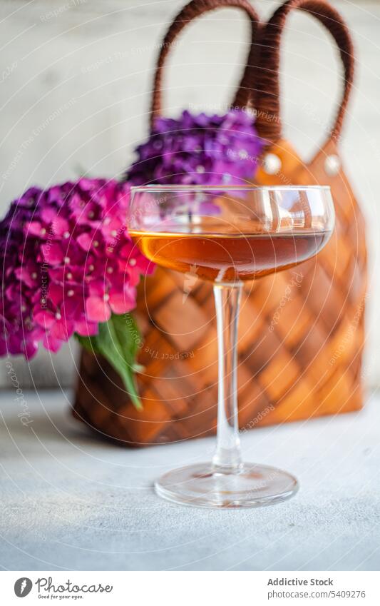 Flowers near glass with drink flower bloom blossom bouquet decoration beverage fresh natural floral alcohol purple table plant bunch basket bag petal liquid