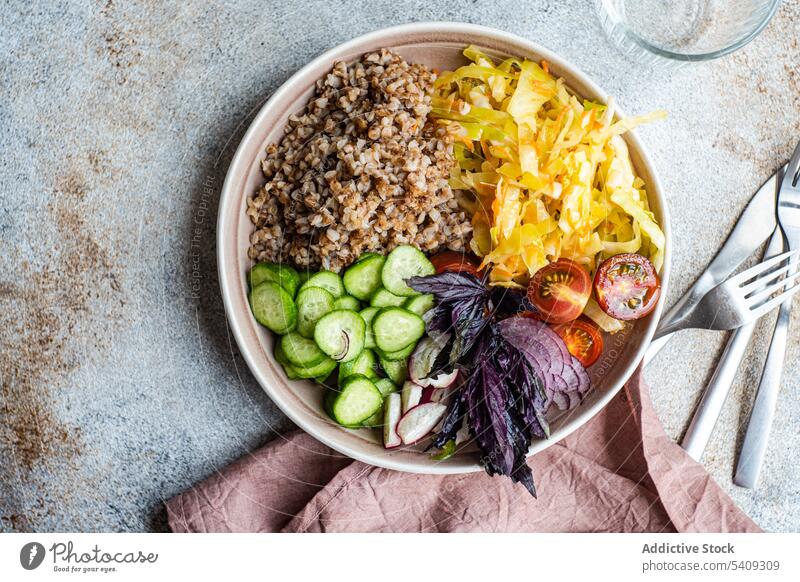 Plate with delicious veggie meal, cutlery and glasses on table vegetarian buckwheat vegetable onion cucumber tomato basil bowl salad herb weight loss healthy